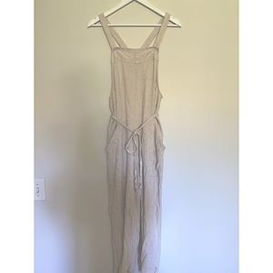 Long romper/ overalls. Tie around waist to adjust size. Light cream in color.
